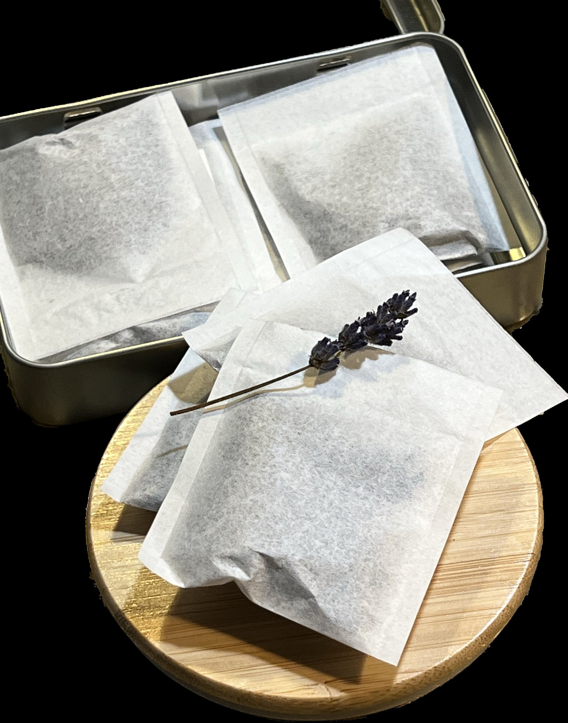 An opened tin box of lavender sachets, sitting alongside a grouping of sachets, providing a clear view of the product packaging.