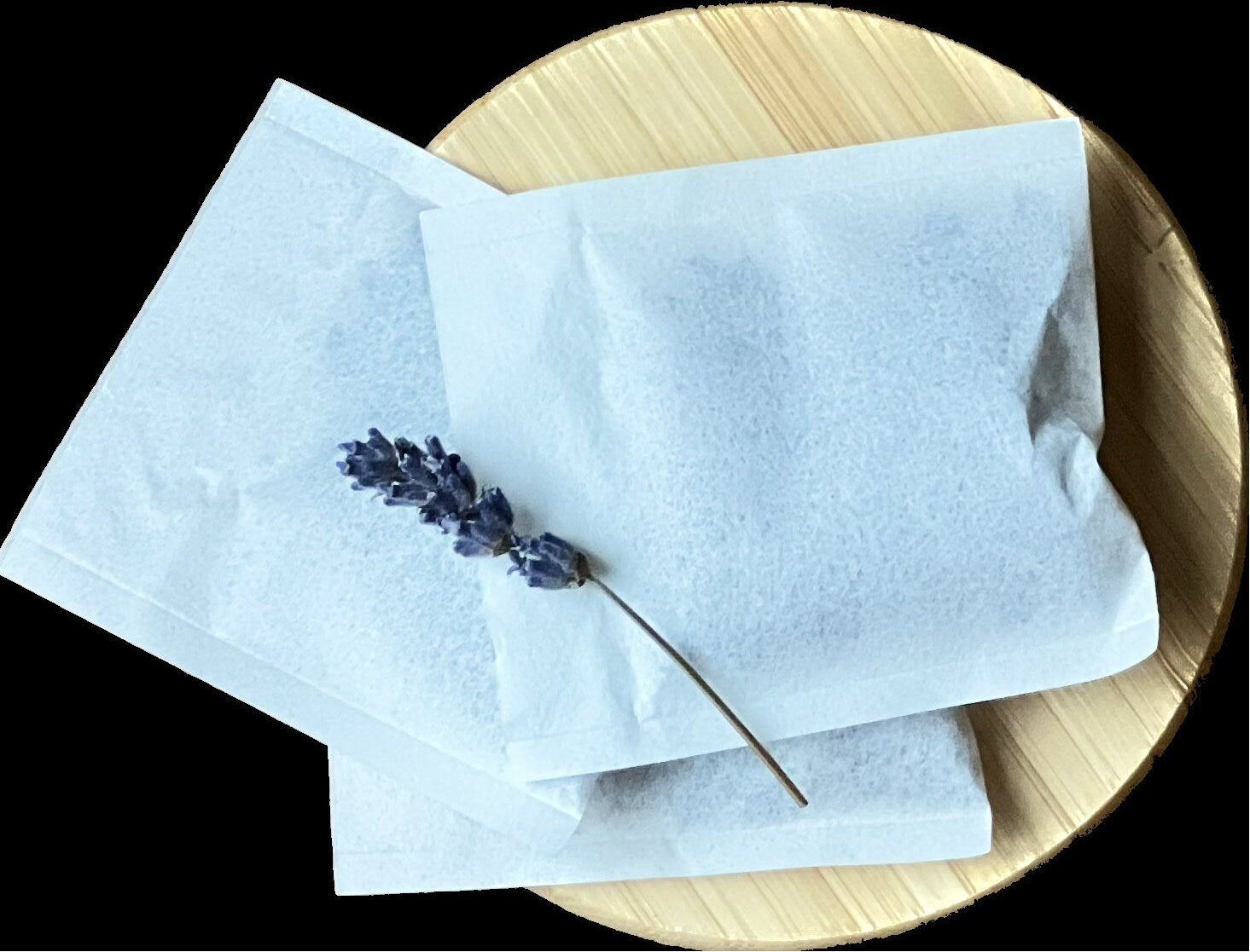 A view of three lavender sachets on with a sprig of dried lavender placed artistically on top of it.