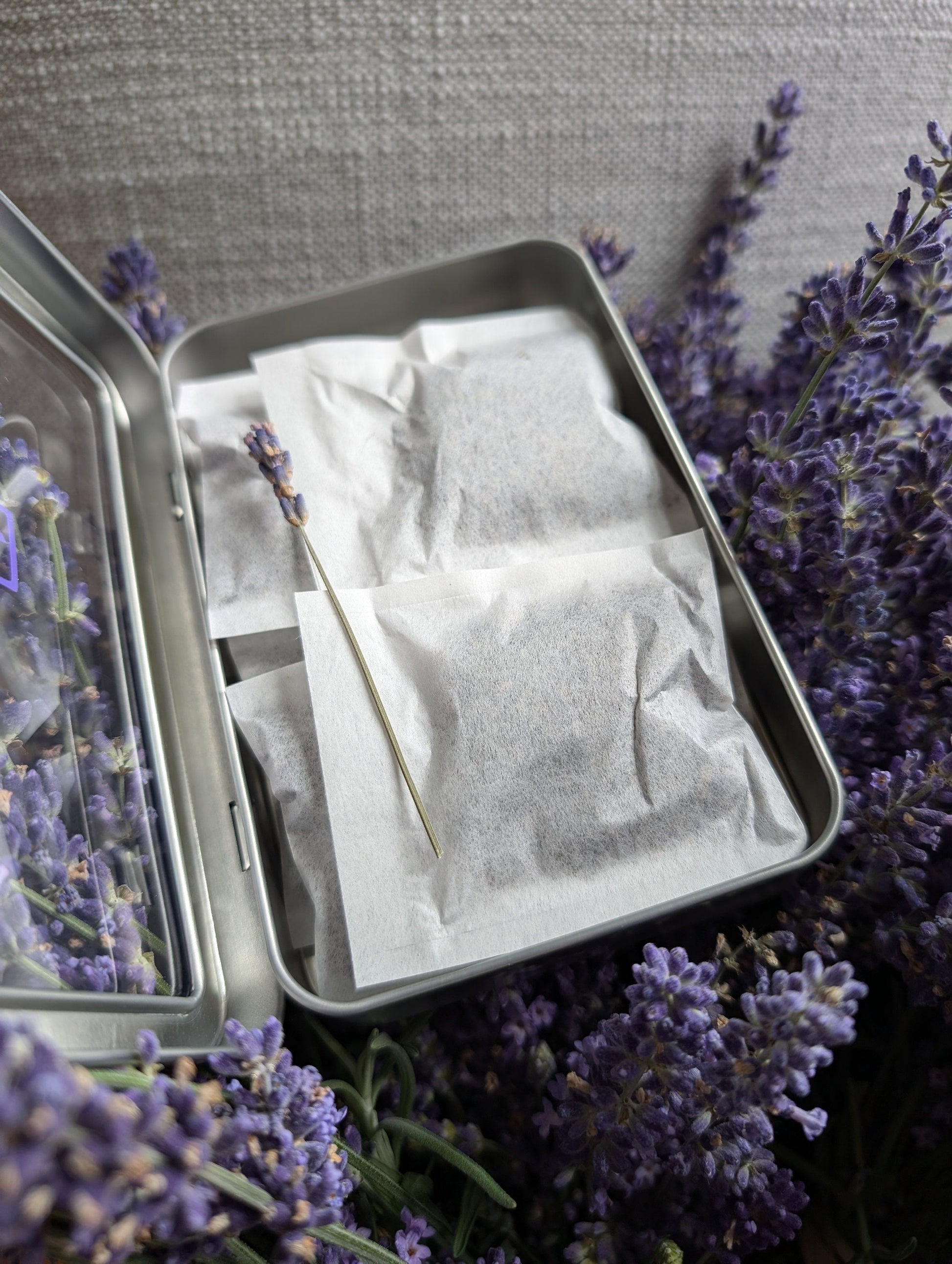 An arrangement of lavender sachets and open tin boxes on a light surface, highlighting their compact and portable design.