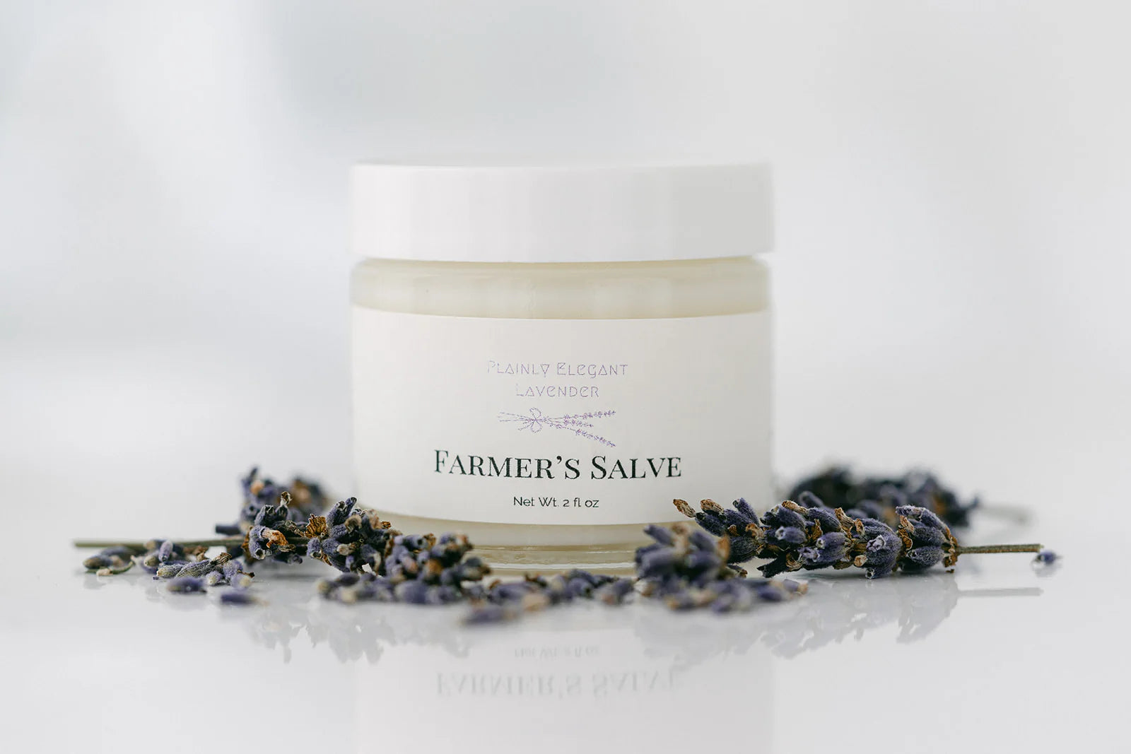 Jar of 'Farmer's Salve' with lavender flowers on a white background