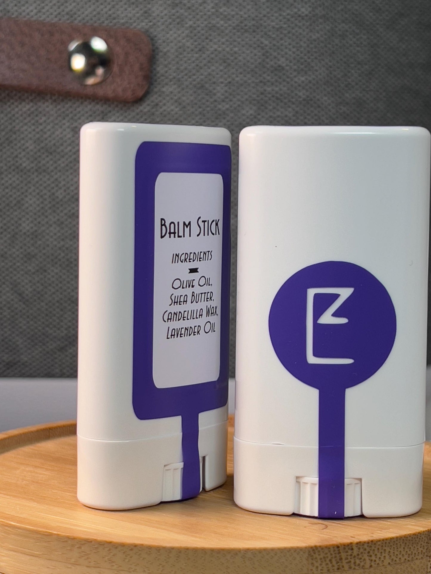 The vegan lavender balm stick is displayed upright showing its compact, travel-friendly design. A solid lotion and perfume bar, made from vegan ingredients, for moisturizing dry skin, front and back are both shown.