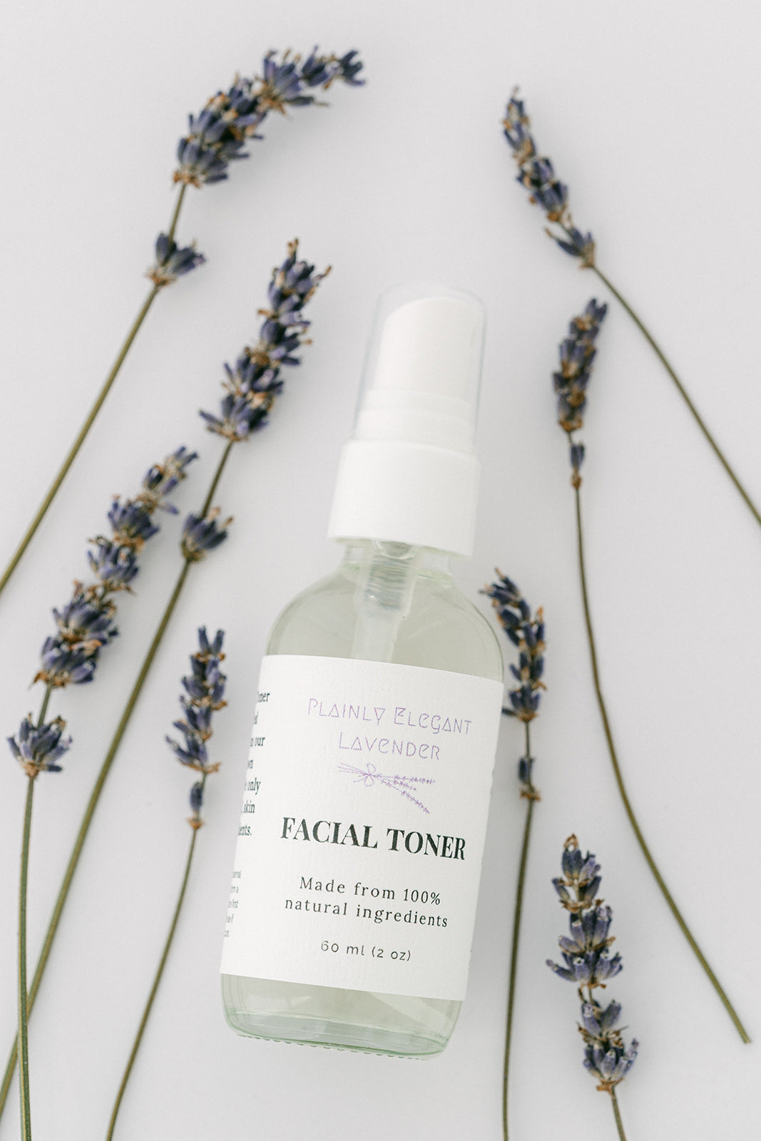 Facial toner bottle with lavender flowers on a light background