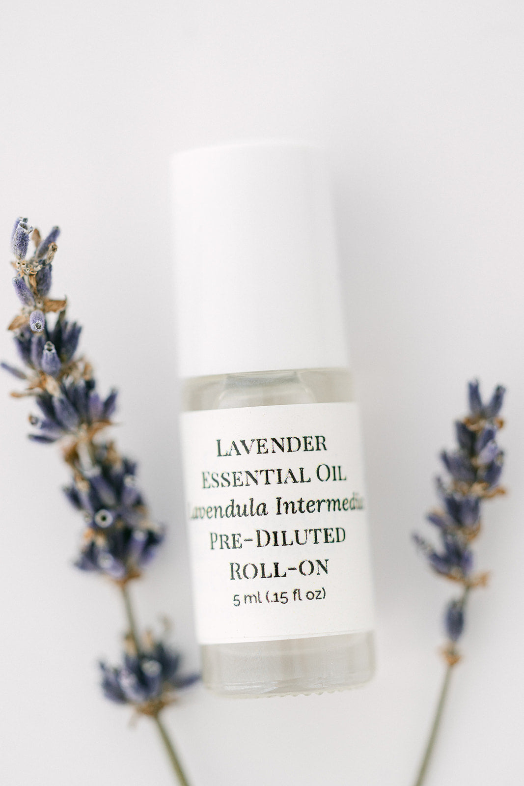 Lavender essential oil roll-on bottle with lavender sprigs on a white background